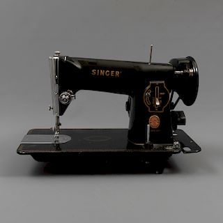 Máquina de coser. México. Siglo XX. Estructura en metal color negro. Marca Singer. No. Serie 104877. Mecanismo eléctrico. Con pedal.