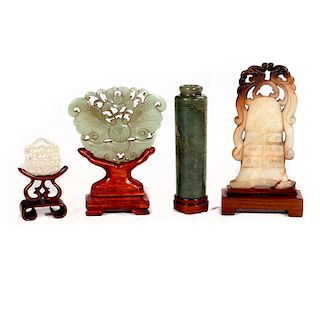 Four Chinese jade sculptures on stands.
