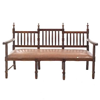Banca. Siglo XX. En talla de madera. Con respaldo semiabierto, asiento acojinado de piel color marrón. Dimensiones: 100 x 162 x 67 cm.