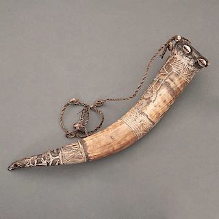 Instrumento musical. Camerún, Siglo XX. Grupo étnico Bamileke. Cuerno tallado, conchas de cauri y fibras naturales. 49 x 8.5 cm