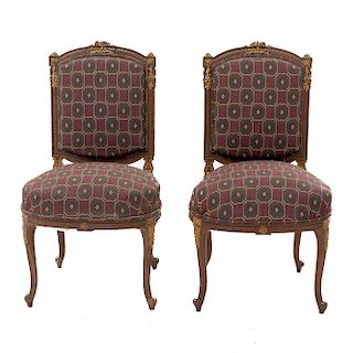 Par de sillas. Siglo XX. En talla de madera. Con respaldos cerrados y asientos acojinados en tapicería color rojo.