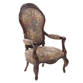 Sillón. Siglo XX. Estilo Victoriano. En talla de madera. Con respaldo cerrado y asiento en tapicería floral, fustes y sortes semicurvos
