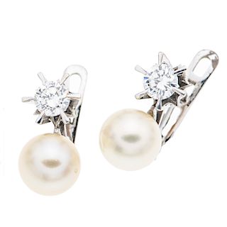 Par de aretes con diamantes y perlas en oro blanco de 18k. 2 perlas color blanco de 8 mm. 2 diamantes corte brillante. Color J.