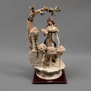 Dama en balcón. Italia. Siglo XX. Diseño de Giuseppe Armani. Elaborada en porcelana Capodimonte. Acabado gres. Con base de madera.