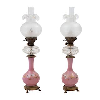 Par de lámparas de mesa. Siglo XX. Elaboradas en cristal de leche color rosa decorados con motivos florales. Soportes de metal dorado.