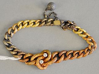 14K tricolor gold bracelet designed with tapered carved links with central knot mounted with two mine cut diamonds and safety chain ...
