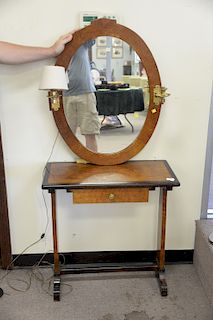 An English yew wood writing table and oval mirror with banded top over a single drawer, on trestle supports, late 19th/20th century....