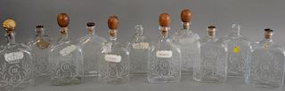Group of eleven English etched glass decanters, each with rectangular section, one side wheel engraved with a George III style cyphe...