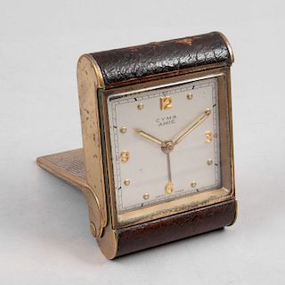 Reloj de viaje. Suiza, siglo XX. De la marca CYMA. Estructura de metal dorado con aplicación de piel. Con carátula cromada.