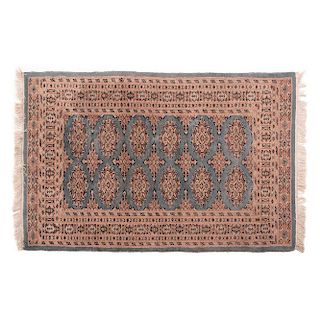 Tapete. Pakistán, siglo XX. Estilo Bokhara. Elaborado en fibras de lana con ensedado sobre fondo azul y rosa.