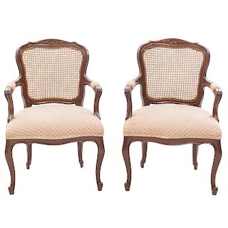 Par de sillones. Siglo XX. En talla de madera. Con respaldos cerrados de bejuco, asientos acojinados en tapicería geométrica.