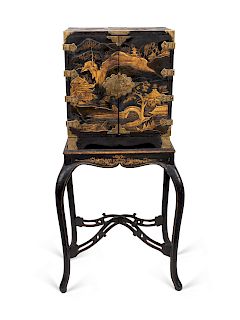 A Japanese Export Gilt Metal Mounted Black and Gilt Lacquer Cabinet on Later Stand
19TH CENTURY
the front doors decorated with landscape views, the to