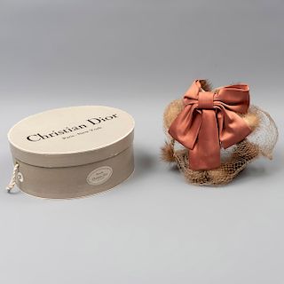 Sombrero para dama. Marca Christian Dior. Estados Unidos. Siglo XX. Elaborado en kanekalon y tela. Con moño y caja original.