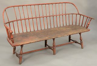 Windsor bow back settee, with old red paint, spindles missing, refinished, 18th century. length 64 inches.