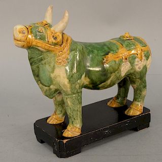 A sancai glazed pottery figure of a caparisoned bull, body glazed green, the trappings glazed in cream and amber. length of wood stand 8 1/2 inches. P