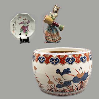 Lote mixto de 3 piezas. Origen oriental. SXX. En porcelana y cerámica. Consta de: mujer con instrumento musical, pecera y plato.