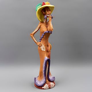 Catrina fumando. México. Siglo XX. En barro policromado. Vestida con vestido marrón, collar, sombrero y aretes. 52 x 16 x 16 cm.