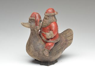 A wooden carving of Santa Claus riding on a duck.