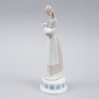 Figura de niña y pato con caja musical. España, siglo XX. Elaborada en porcelana Lladró acabado brillante, mecanismo de cuerda.