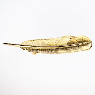 A YELLOW METAL BROOCH BY HERMES, modelled as a feather, on 