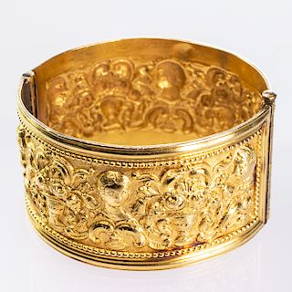 A RENAISSANCE STYLE BANGLE, the wide band with elaborately 