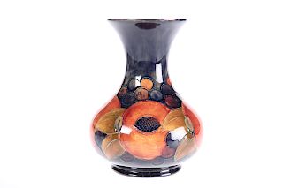 A WALTER MOORCROFT POTTERY VASE, the squat body with trumpe