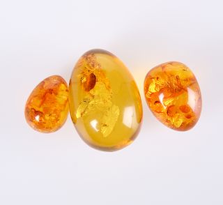 A GROUP OF THREE AMBER COLOURED EGGS. Largest 4.5cm