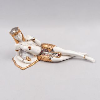 Cleopatra recostada. España, siglo XX. Elaborada en porcelana Nadal acabado brillante con detalles en esmalte dorado y plateado.