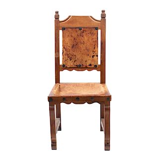 Silla. Siglo XX. Elaborada en madera tallada y piel. Respaldo semiabierto y asiento en piel con aplicaciones de remaches.