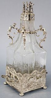 Figural Silver and Crystal Decanter Set, having four etched bottles with mounted putti handles and figural silver stoppers in silver square base with 