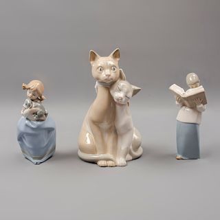 Lote de 3 figuras decorativas. España. 1987. En porcelana, una Nao. Consta de: monaguillo, niña con perro y pareja de gatos.