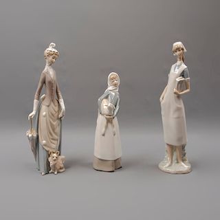 Lote de 3 figuras decorativas. España. Ca 1960. En porcelana Lladró. Consta de: enfermera, dama con perro y paragüas y niña con cordero