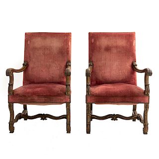 Par de sillones. Francia. Siglo XX. En talla de madera de nogal. Con respaldos cerrados y asientos acojinados en tapicería color rojo.