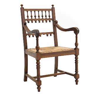 Sillón. Francia. Siglo XX. Estilo Enrique II. En talla de madera de nogal. Con respaldo semiabierto y asiento de palma tejida.