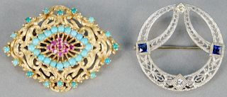 Two gold brooches, 14K white gold circle brooch with blue sapphires and two diamonds along with a brooch with turquoise and red stones. total weight 1