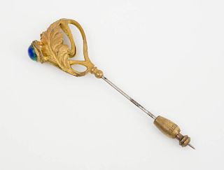 GILT-METAL FRAME BROOCH AND A GOLD AND GLASS STICK PIN