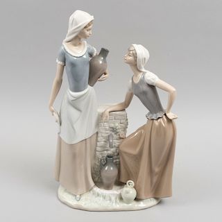 Firgura de mujeres recolectoras de agua. España, siglo XX. Elaborada en porcelana Nao acabado brillante. 40 cm de altura.