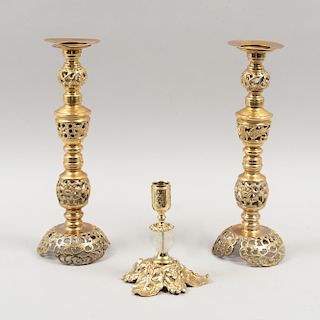 Lote de candeleros. Siglo XX. Elaborados en latón dorado, con calados y uno con motivo esférico de cristal opaco. Pz: 3