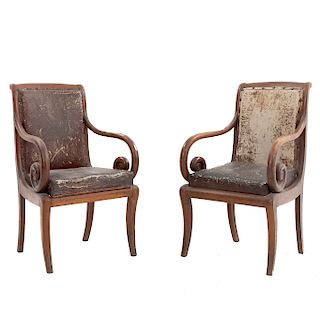 Par de sillones. Siglo XX. En talla de madera. Con respaldos cerrados y asientos acojinados en piel color marrón.