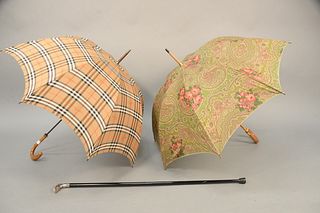 Three piece lot to include a Burberry plaid umbrella with wood handle along with Lancel paisley umbrella, along with a walking stick. stick lg: 37" . 