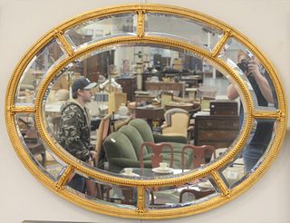 Oval contemporary mirror having gold frame and beveled glass mirror. 26" x 48".