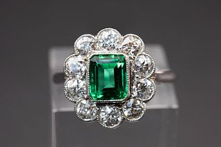 AN EMERALD AND DIAMOND RING, the rectangular cut emerald set within a scall