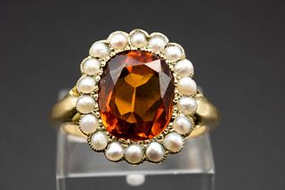 A CITRINE AND SEED PEARL RING, the oval cut citrine set within a surround o