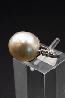 A LARGE PEARL RING, the pearl set simply between diamond set shoulders. Rin