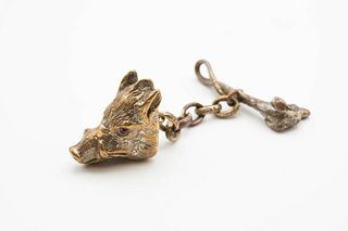 A WHITE METAL HUNTING CLOAK CLASP, modelled as a boar's head with red glass