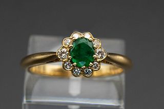 AN 18CT YELLOW GOLD, EMERALD AND DIAMOND RING, the oval cut emerald set wit