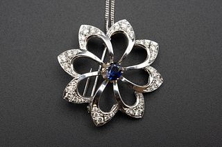 A SAPPHIRE AND DIAMOND BROOCH PENDANT, the open work flower head mount with