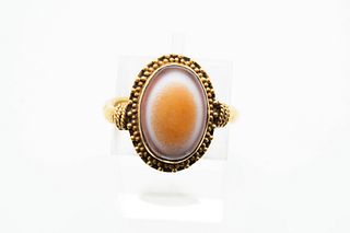 AN AGATE EYE RING, the oval agate within beaded detail mount on textured mo
