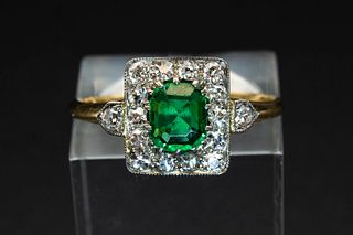 AN EMERALD AND DIAMOND RING, the central oval cut emerald set within a surr