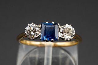 A SAPPHIRE AND DIAMOND RING, the square cut sapphire set between two brilli